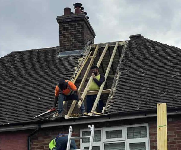 This is a photo of a roof repair being carried out. A section of the roof has been stripped and two roofers are replacing the rafters. Works being carried out by DGH Roofing Armthorpe